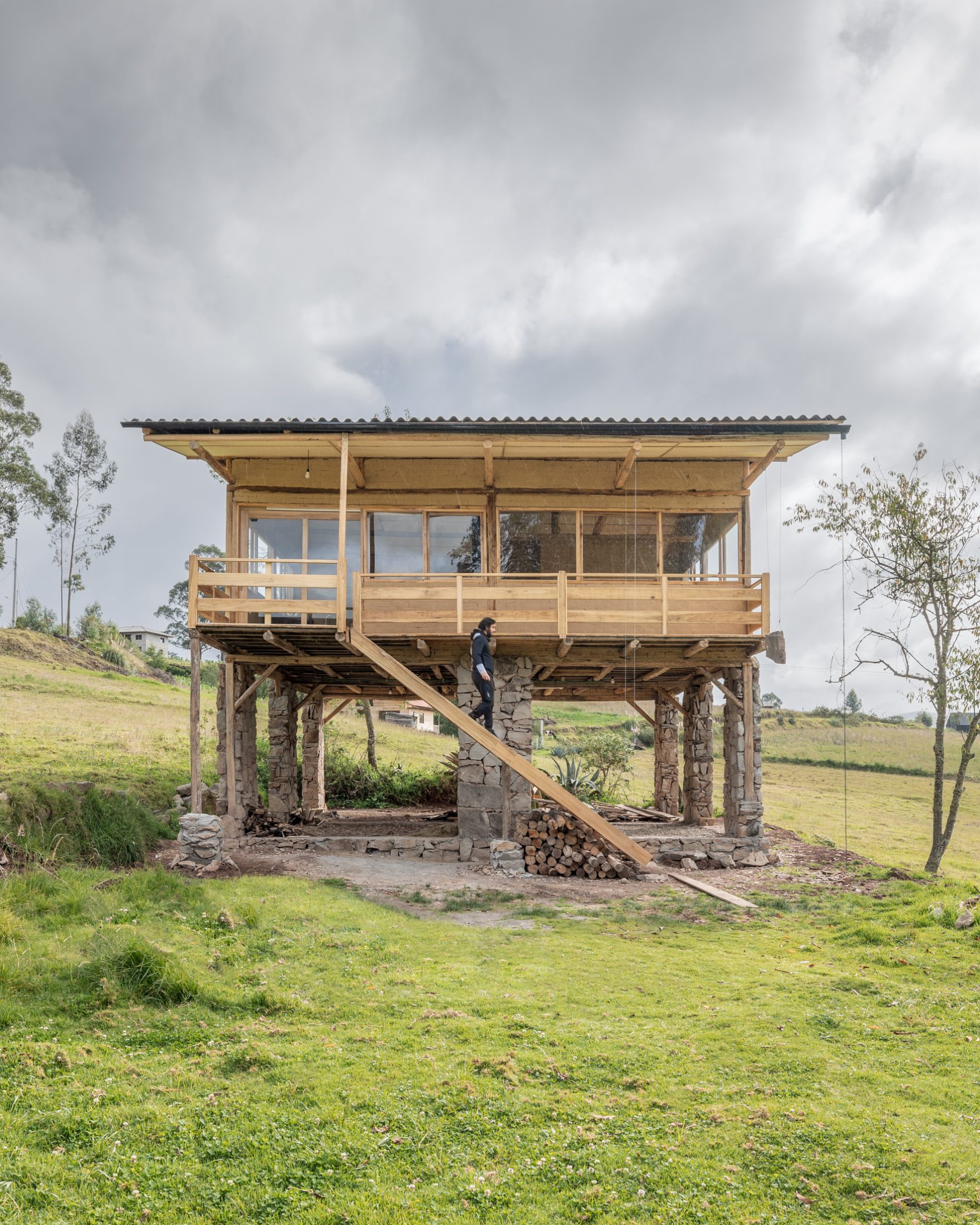 Casa Cojitambo — vivienda elevada sobre columnas de piedra, escalera de madera y dueno sobre la plataforma