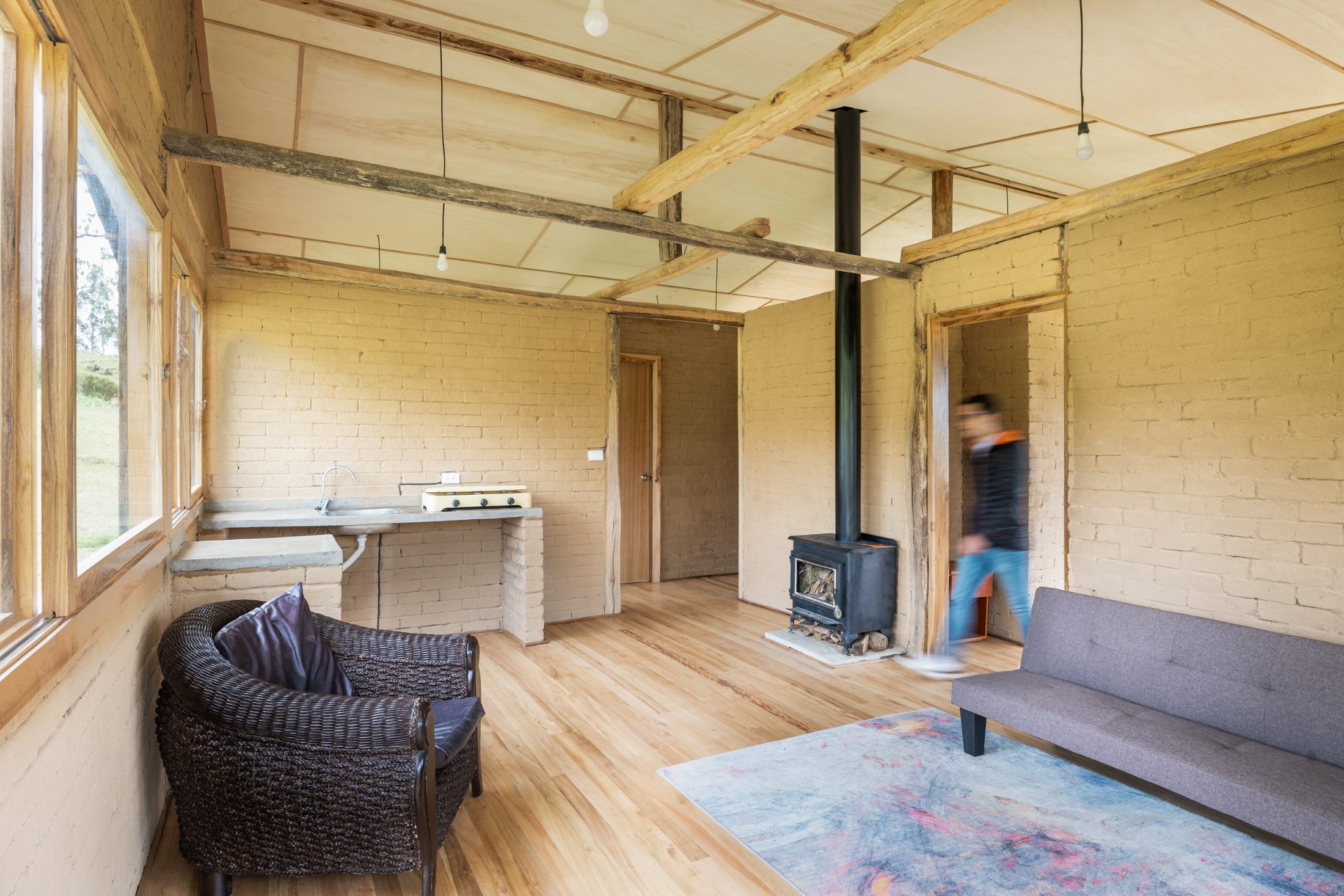 Casa Cojitambo — interior en planta alta con muros de adobe, estufa de leña y cubierta de madera