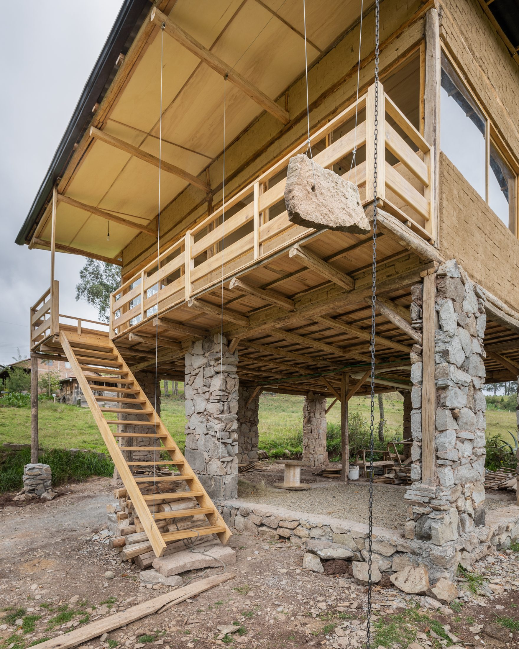 Casa Cojitambo — detalle de la escalera plegable y la piedra de contrapeso suspendida sobre las columnas de piedra