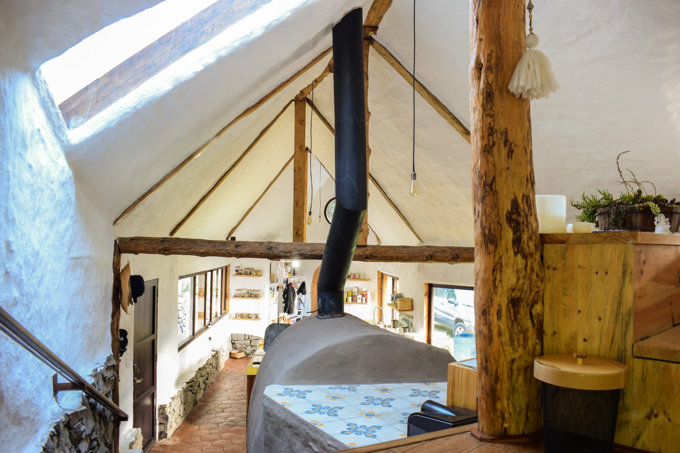 Casa Tarqui — cocina bajo cubierta a dos aguas con vigas de eucalipto y chimenea