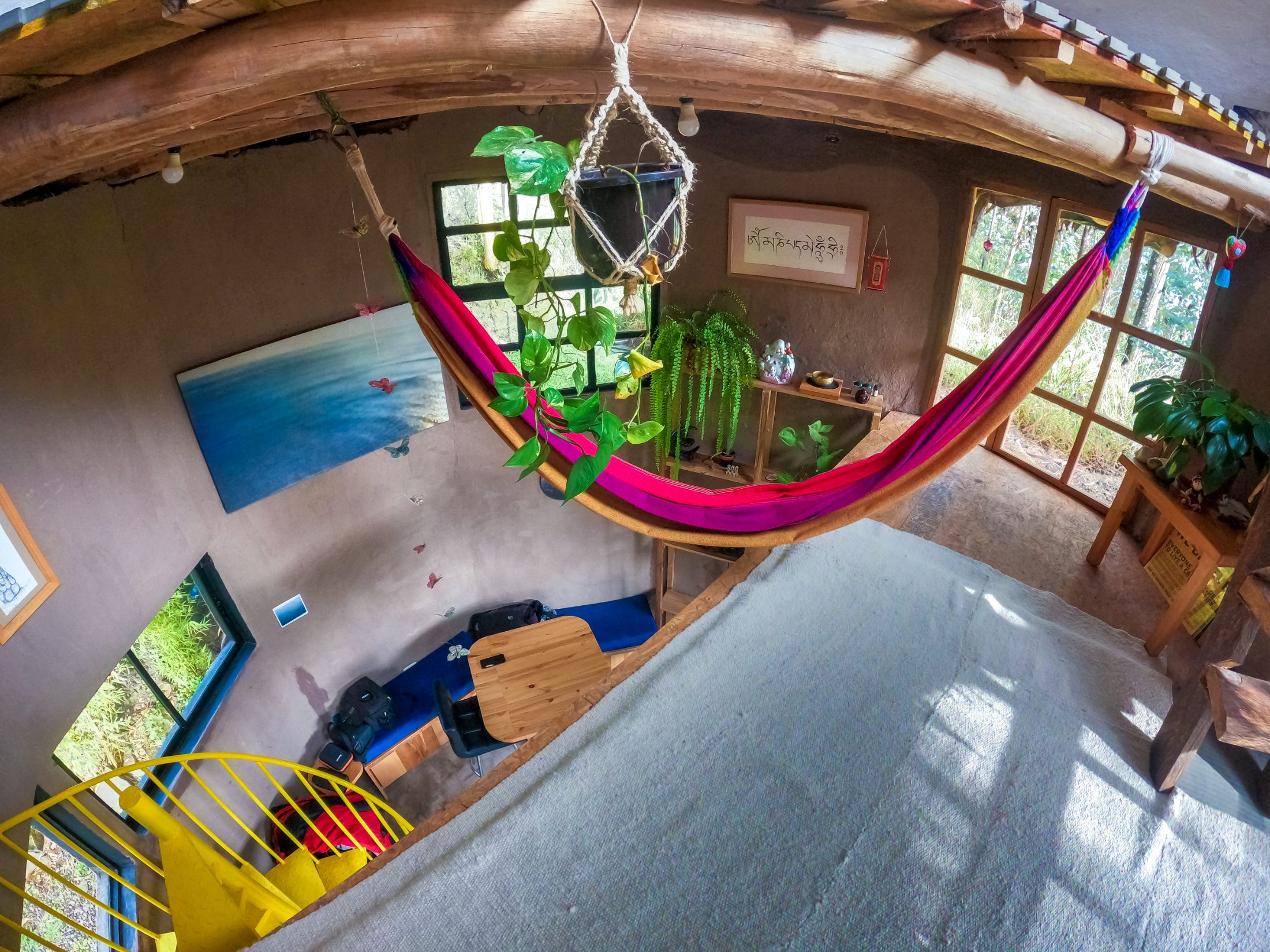 Refugio Cojitambo — interior con hamaca, escalera caracol amarilla y muros de tierra