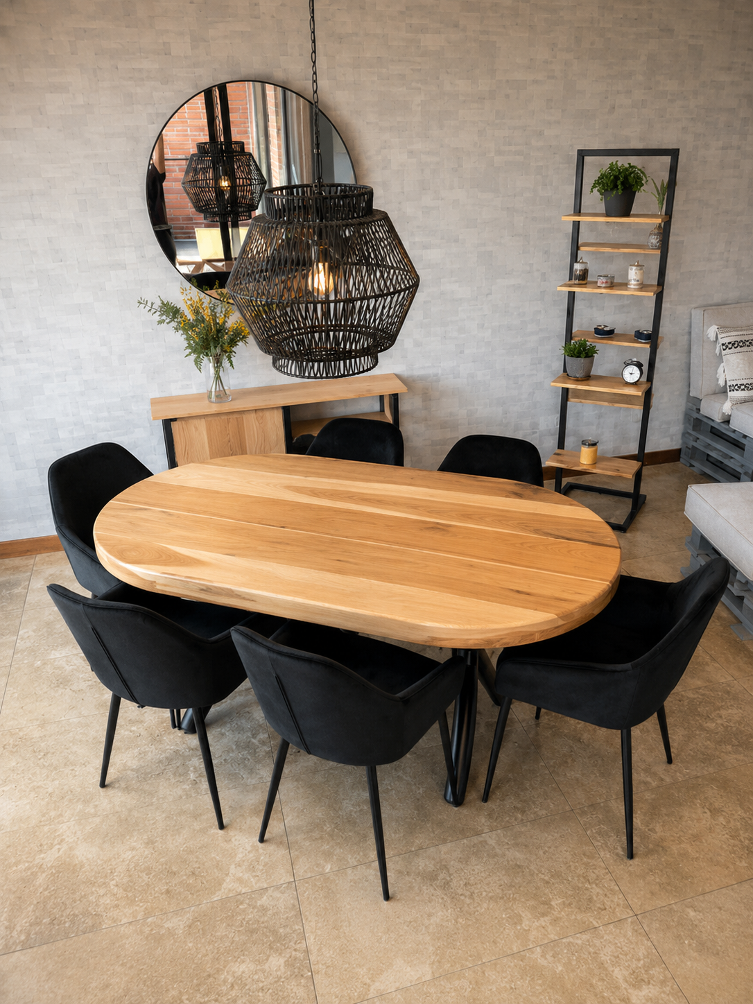Comedor con mesa oval de tablero macizo sobre base metálica negra, estantería de baldas escalonadas con estructura de acero y mueble bajo bajo un espejo redondo