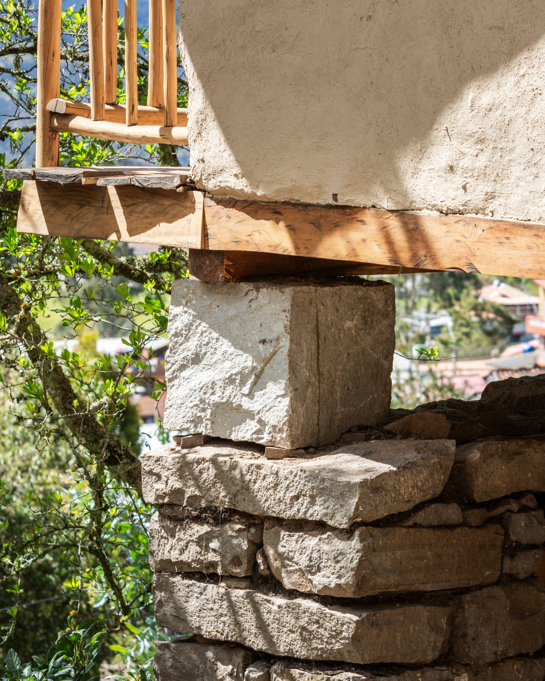 Detalle de cimiento — sillar pre-hispánico bajo viga de madera y muro de tapial blanqueado
