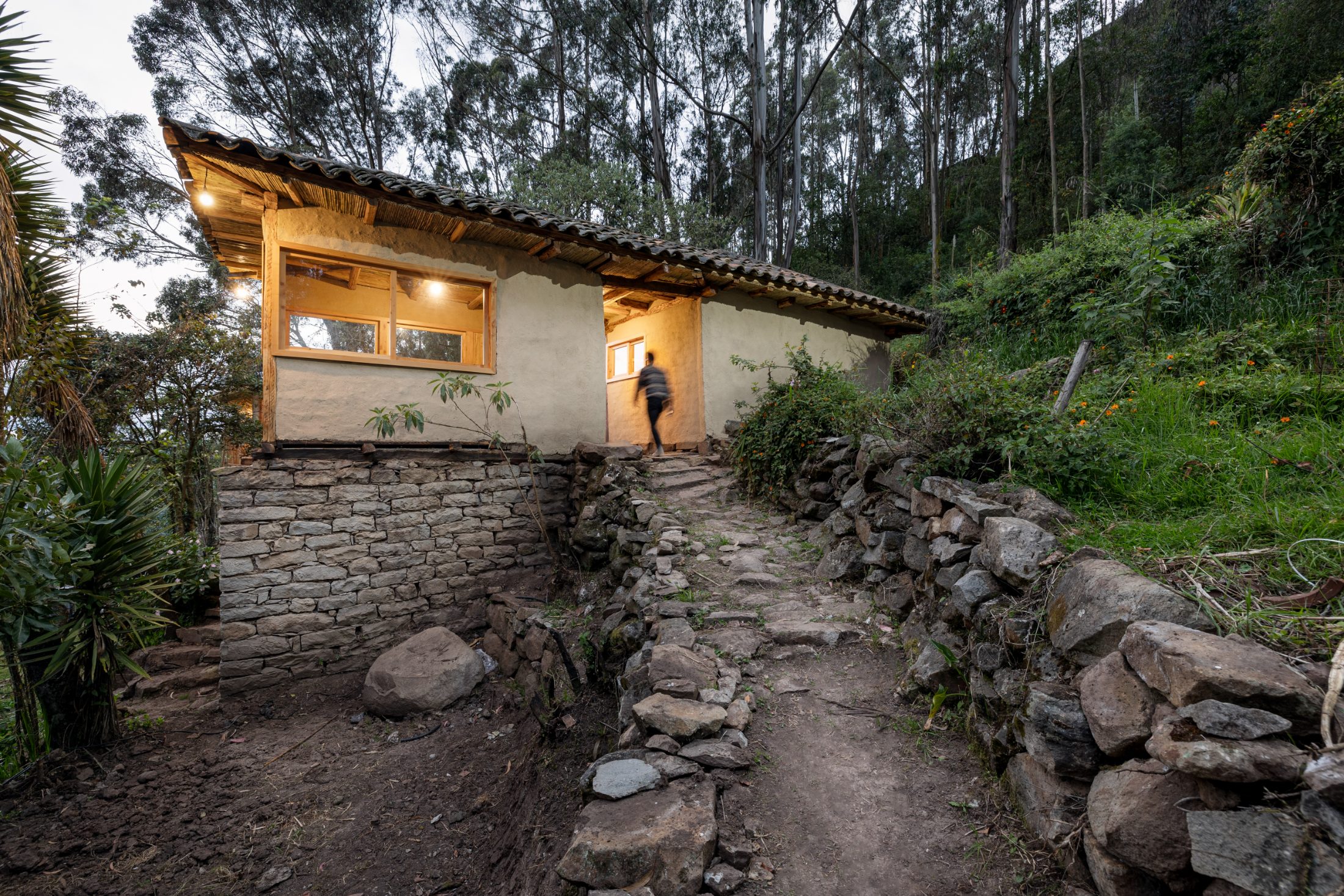KANTUTA — fachada larga con muros encalados, cubierta de teja sobre madera, sendero de piedra de aproximación