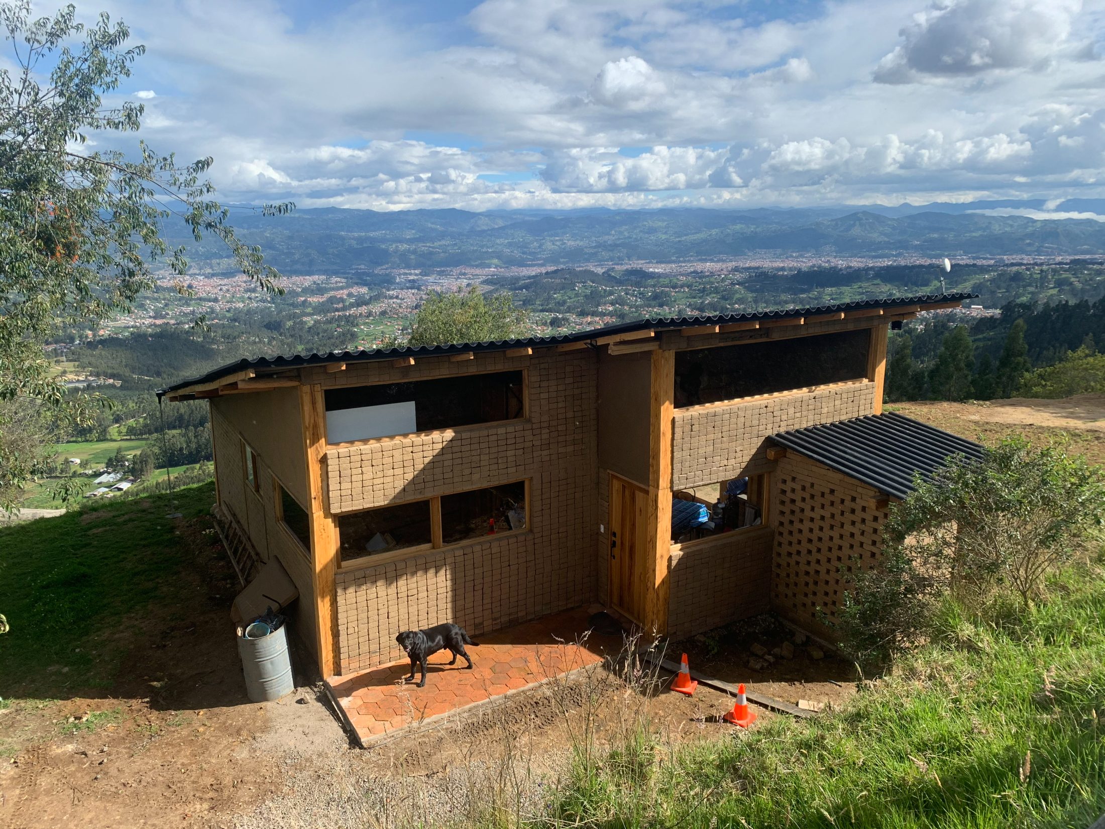 Frente de la casa con piso de baldosa hexagonal y perro labrador, la ciudad de Cuenca al fondo en el valle