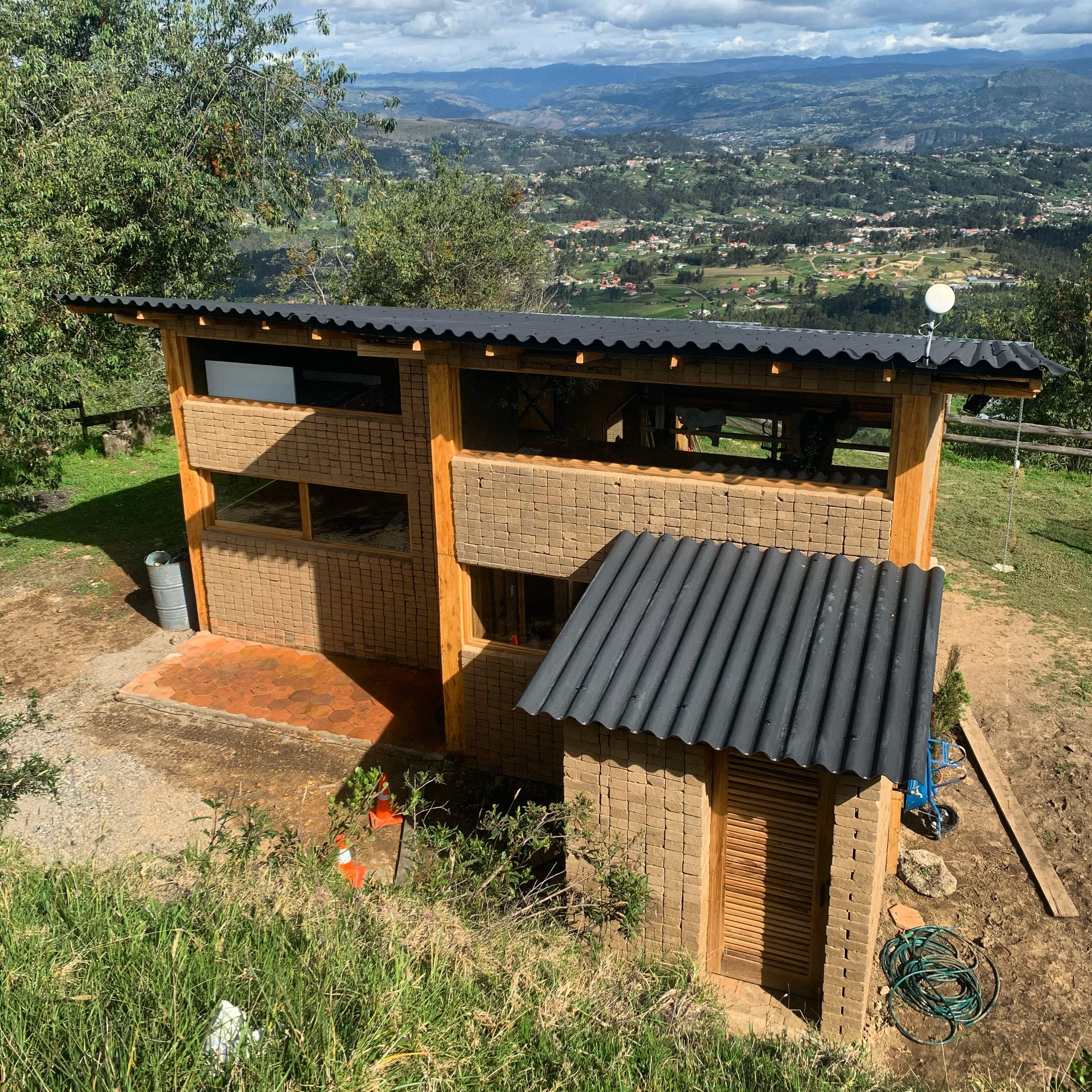 Fachada principal con grandes ventanales hacia el patio y fogata de piedra