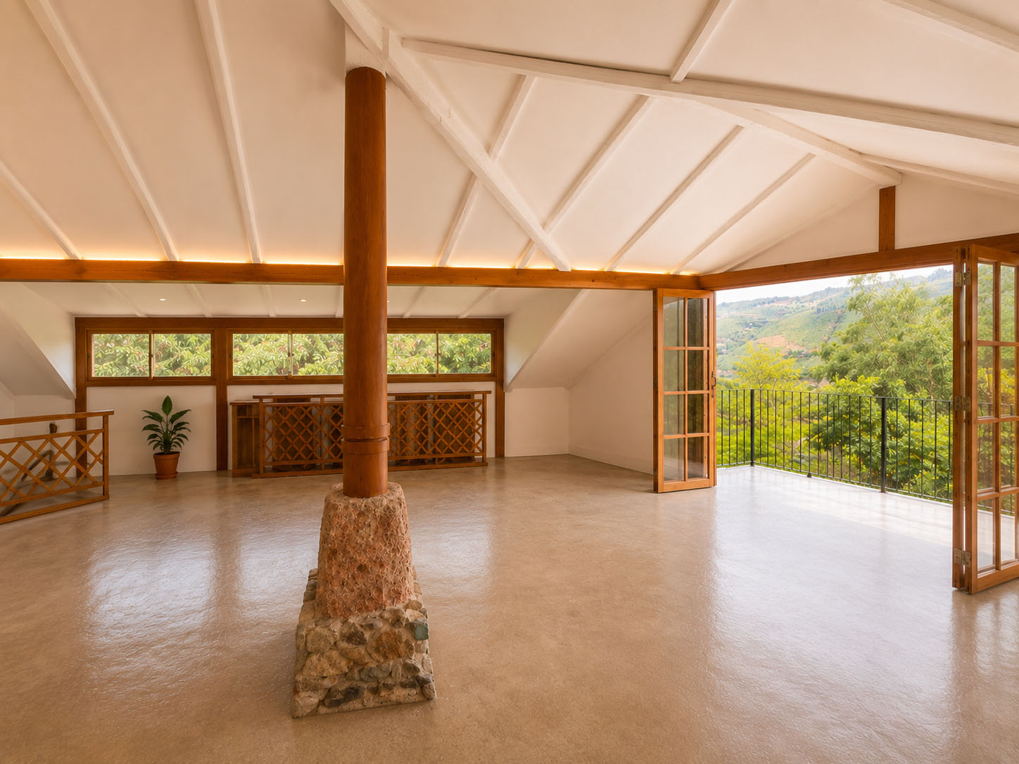 Casa de Tapial, después — la misma planta convertida en gran sala abierta, con la columna de madera sobre base de piedra y puertas plegables al balcón