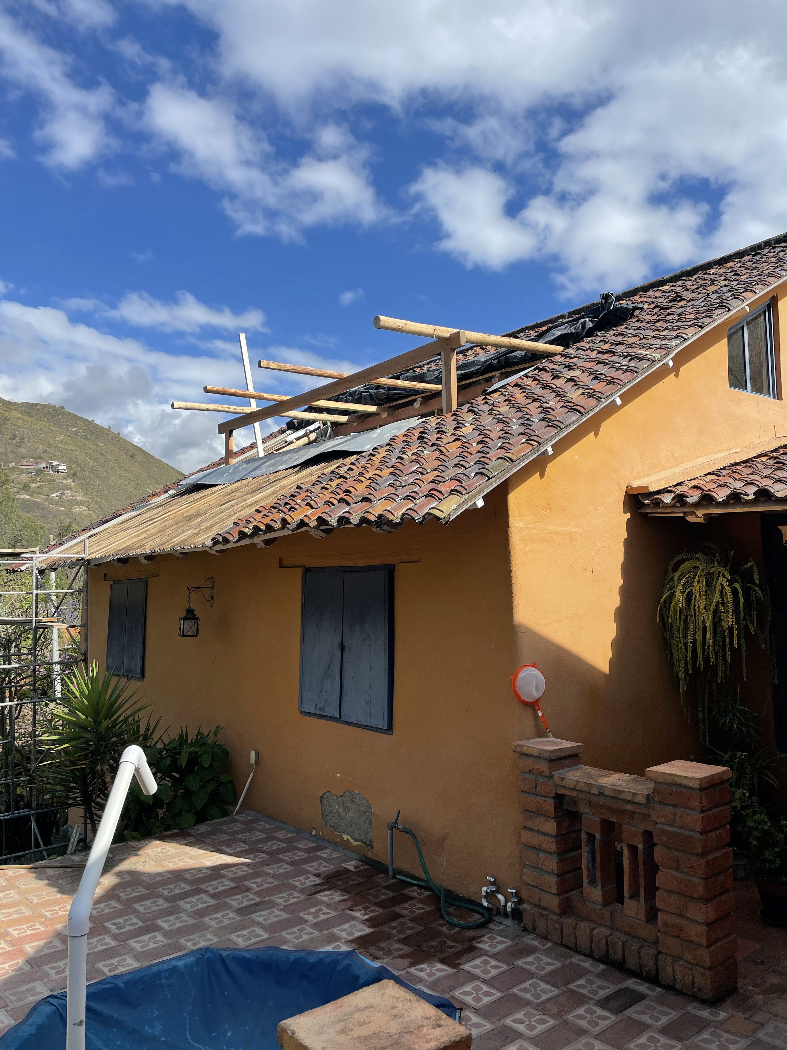Casa de Tapial, proceso — fachada de tierra ocre con el tejado en intervención y andamios sobre el patio